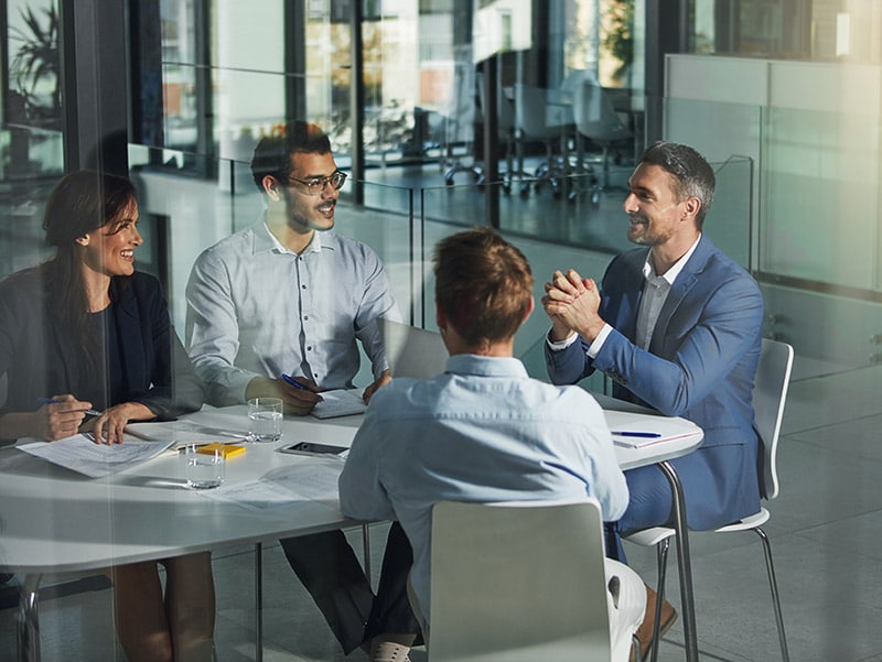 Grupka biznesmenów siedzących przy stole, zdjęcie zrobione przez szybę