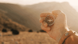 Dłoń trzymająca kompas z widokiem na góry w oddali