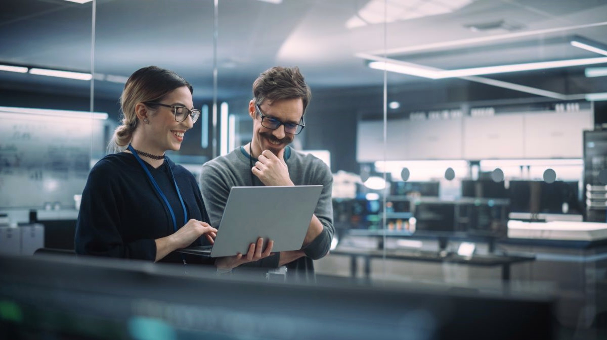 Dwójka współpracowników analizuje dane na laptopie w nowoczesnym biurze, symbolizując współpracę finansów z biznesem jako partnerów wspierających decyzje.